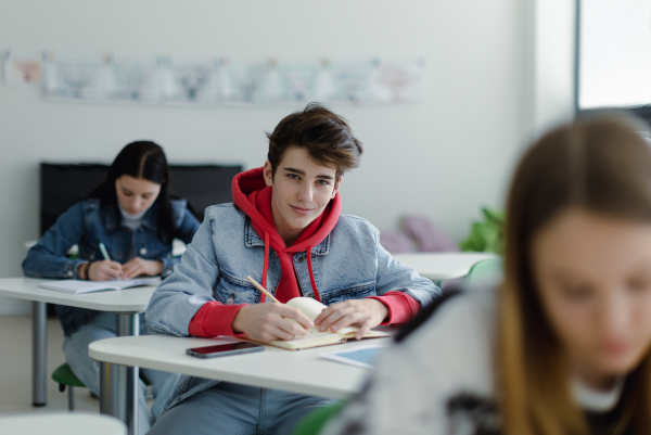 High school students paying attention in a class, sitting in their desks and writing notes, back to school concept.