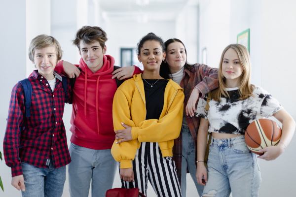 Young high school students walking in a corridor and looking at camera at school, back to school concept.