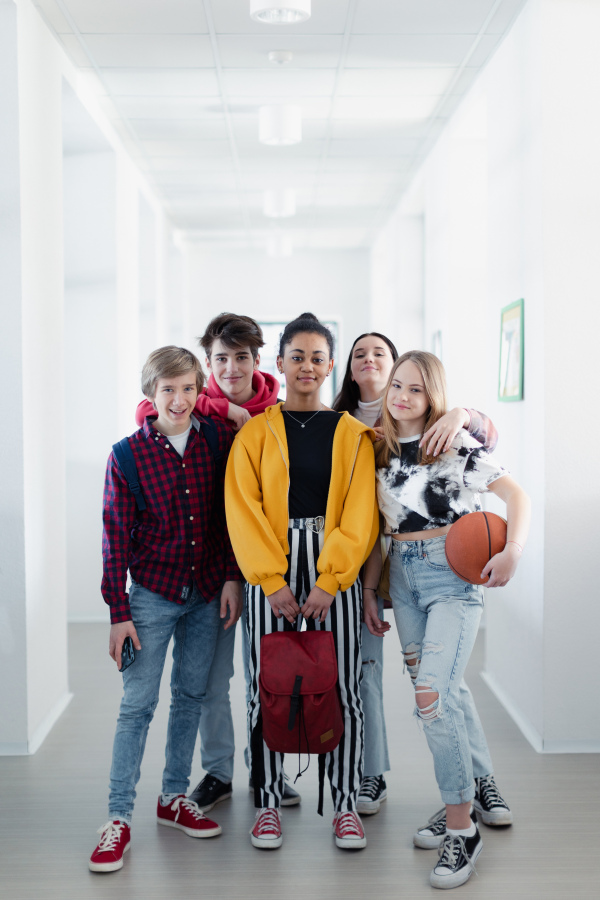 Young high school students walking in a corridor and looking at camera at school, back to school concept.