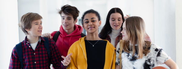 Young high school students walking in a corridor and looking at camera at school, back to school concept.