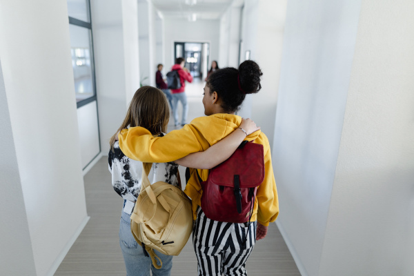 A rear view of young high school students walking in corridor at school, back to school concept.