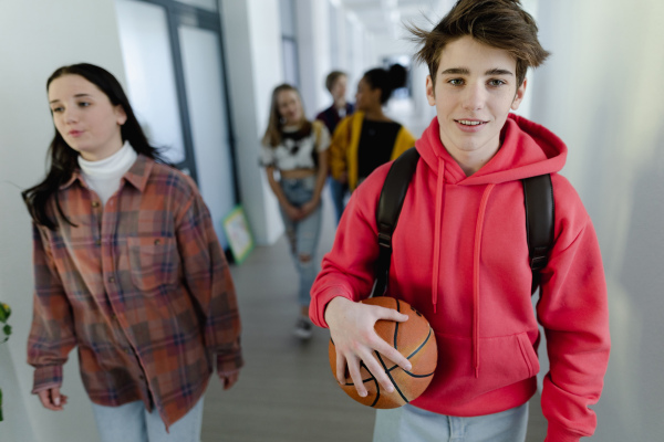 Young high school students walking in a corridor at school, back to school concept.