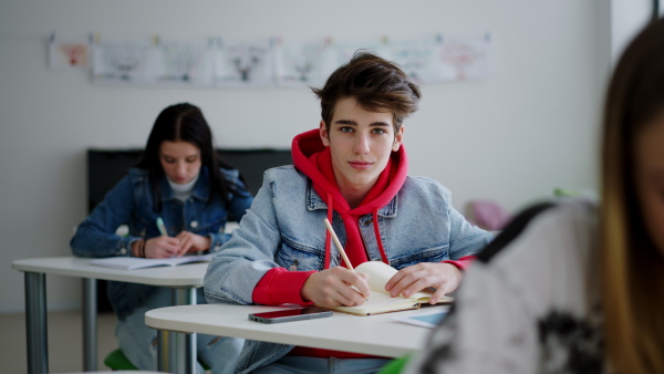 High school students paying attention in a class, sitting in their desks and writing notes.