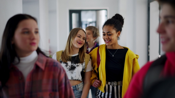 Young high school students walking in a corridor at school, back to school concept.