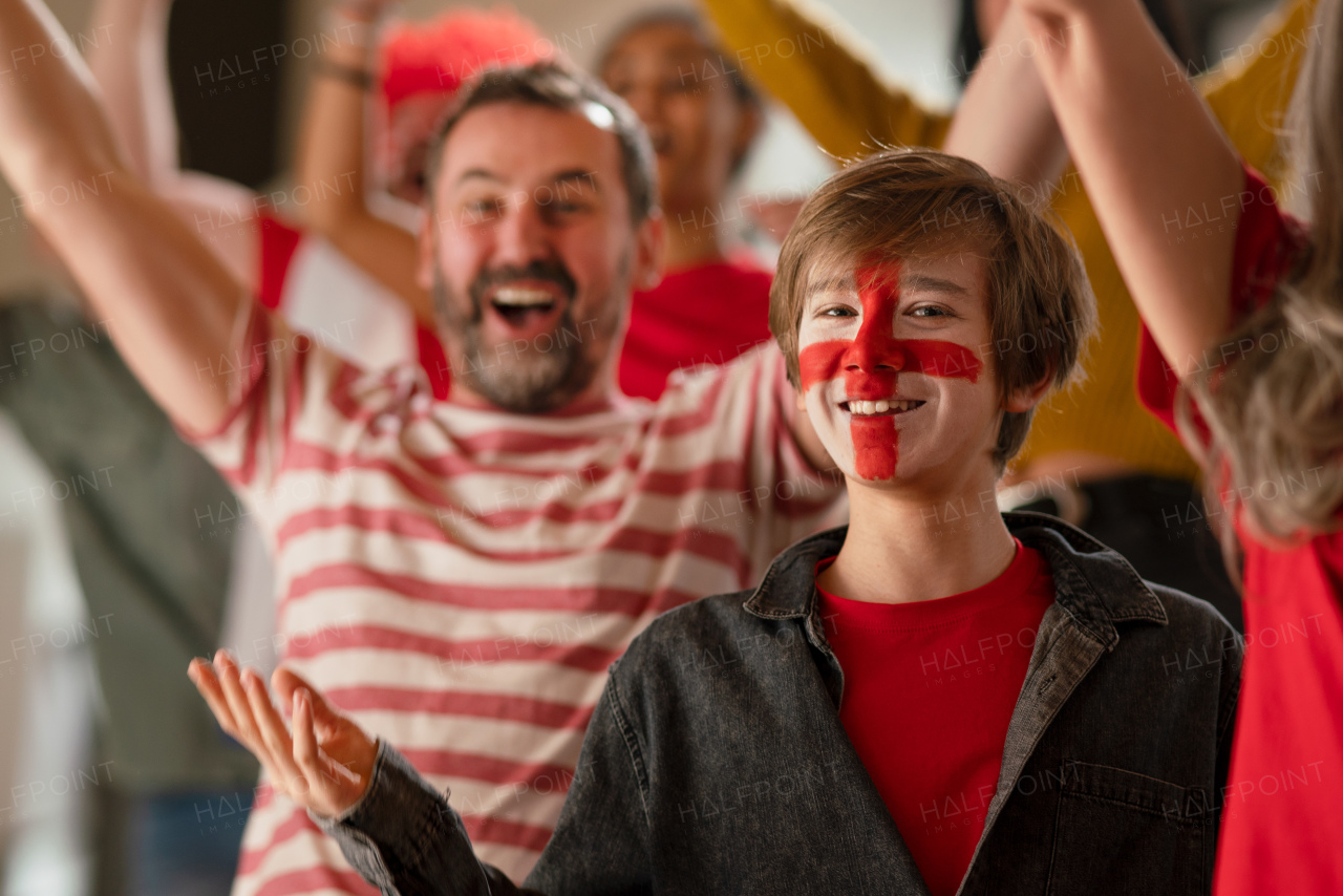 Excited football fans supproting an English national team in live soccer match at stadium.