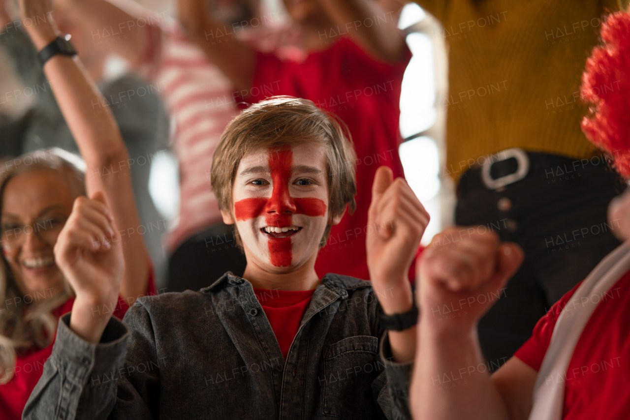 Excited football fans supporting English national team in a live soccer match at stadium.