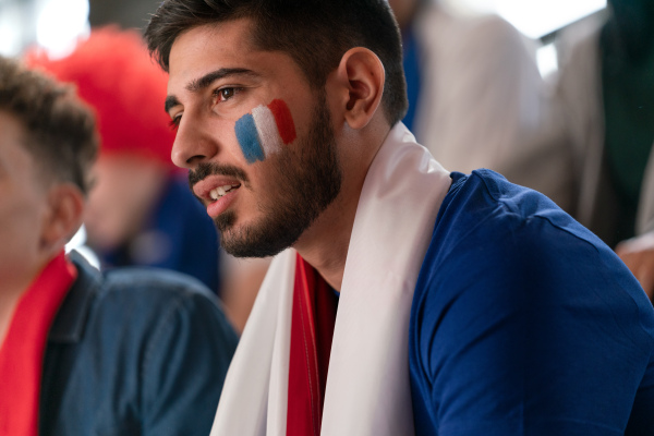 Worried football fans supproting a French national team in live soccer match at stadium.