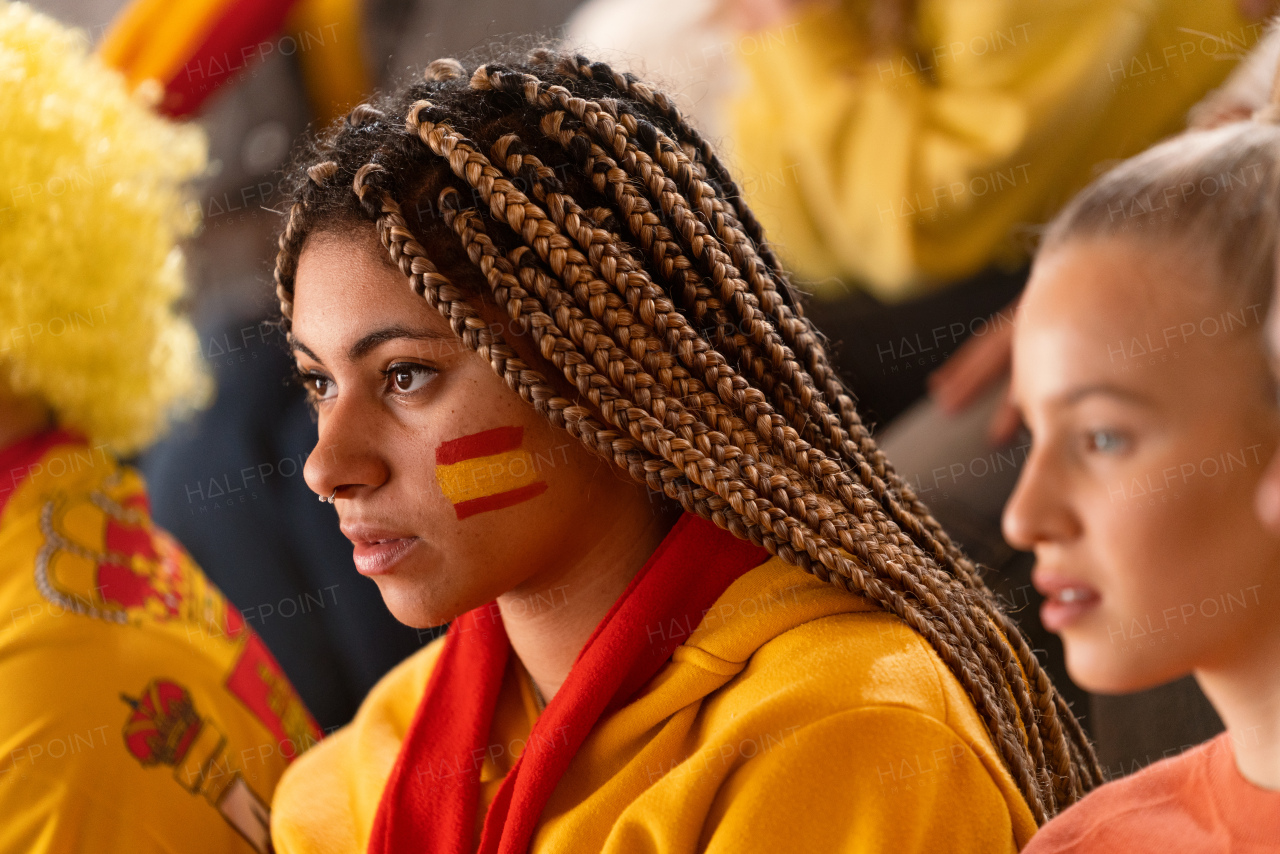 Worried football fans supproting a spanish national team in live soccer match at stadium.