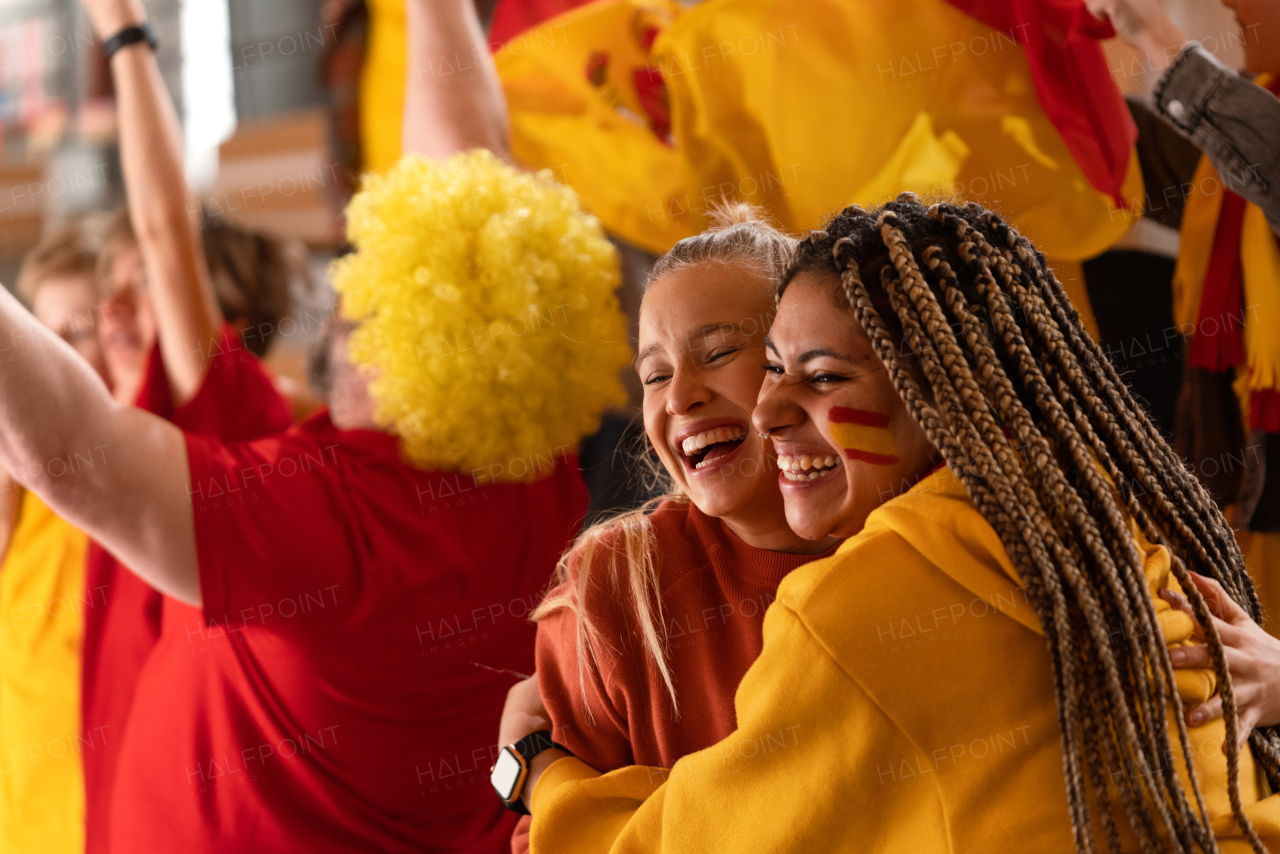 Happy football fans supproting Spanish national team in live a soccer match at stadium, celebrating.