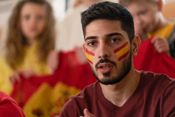 Excited football fans supporting a spanish national team in live soccer match at stadium.