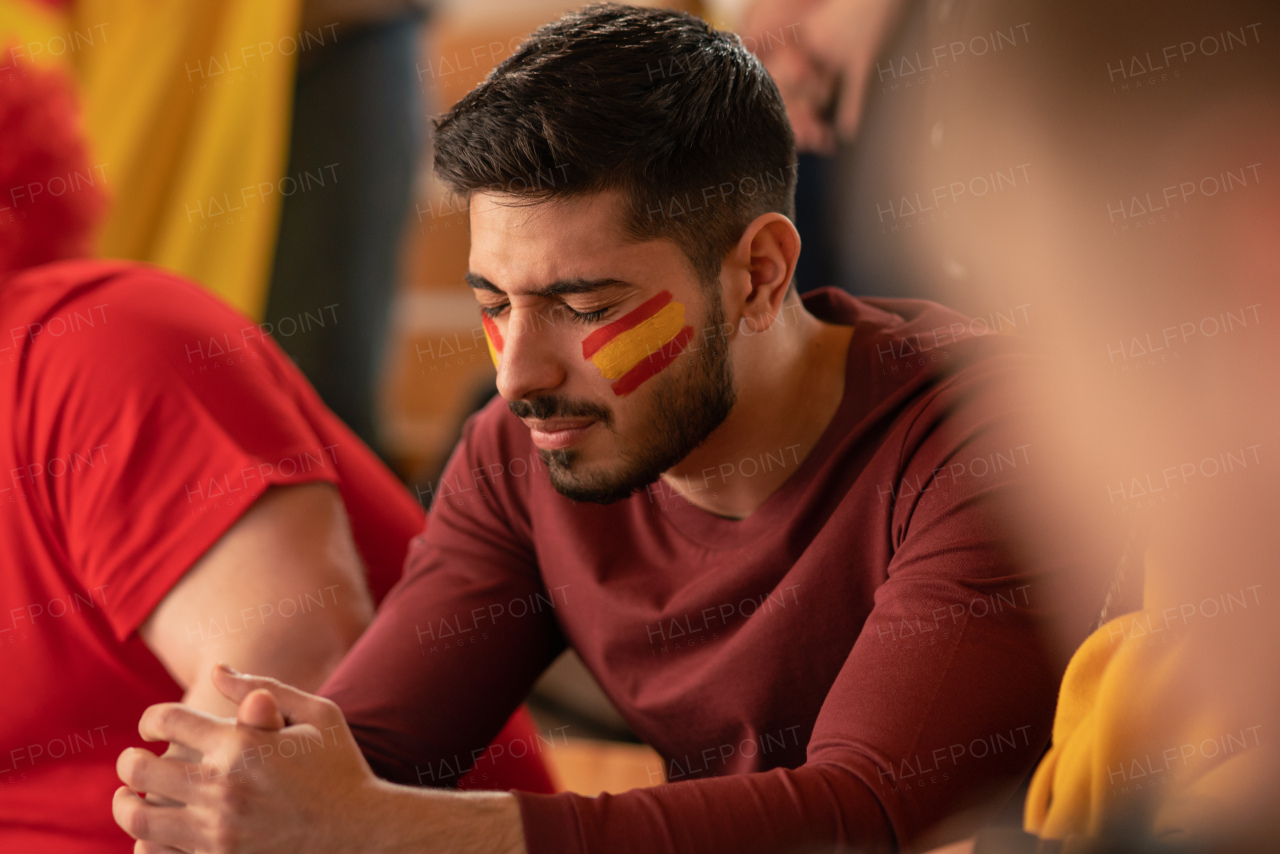 Worried football fans supporting a spanish national team in live soccer match at stadium.