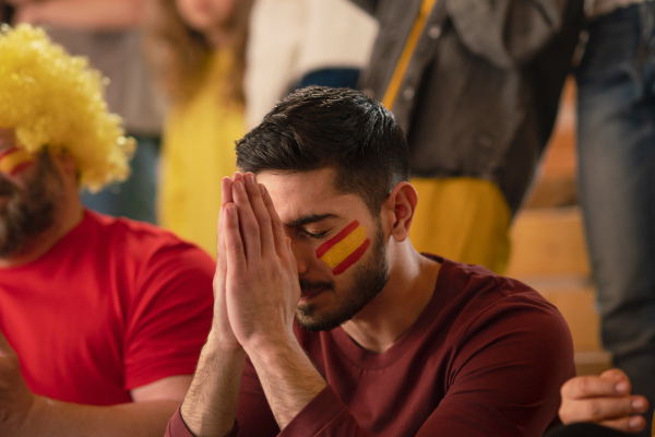 Sad football fan sitting at football stadium a spanish national team in live soccer match.