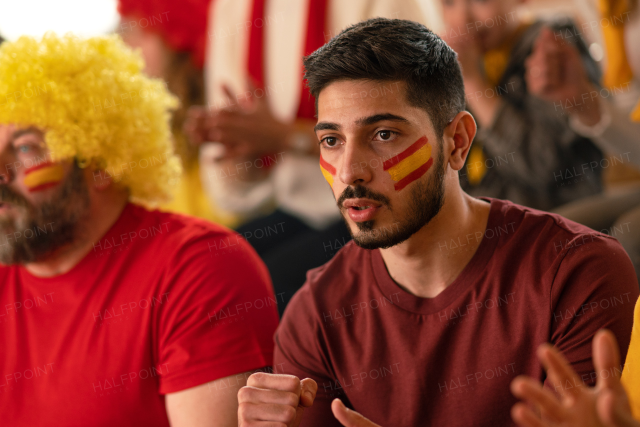 Nervous football fans supproting spanish national team in live soccer match at a stadium.