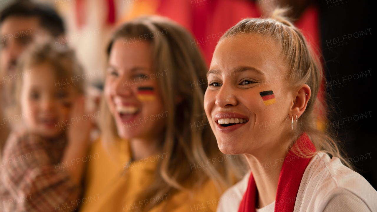 Excited football fans, supproting a German national team in live soccer match at stadium.