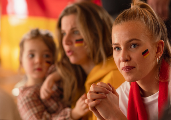 Worried football fans supproting a German national team in live soccer match at stadium.