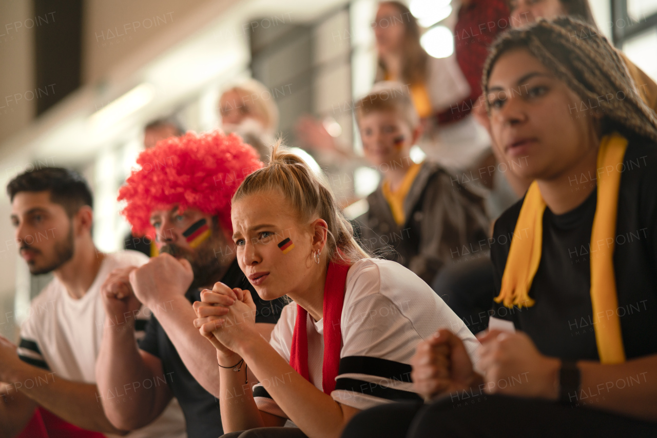 Worried football fans supproting a German national team in live soccer match at stadium.