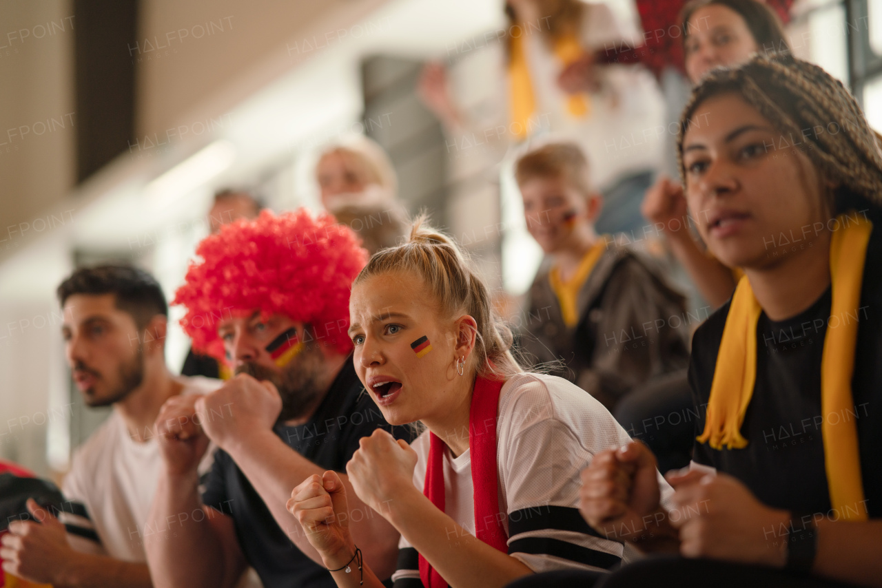 Worried football fans supproting a German national team in live soccer match at stadium.