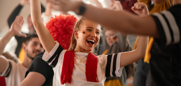 German football fans celebrating their team's victory at a stadium.