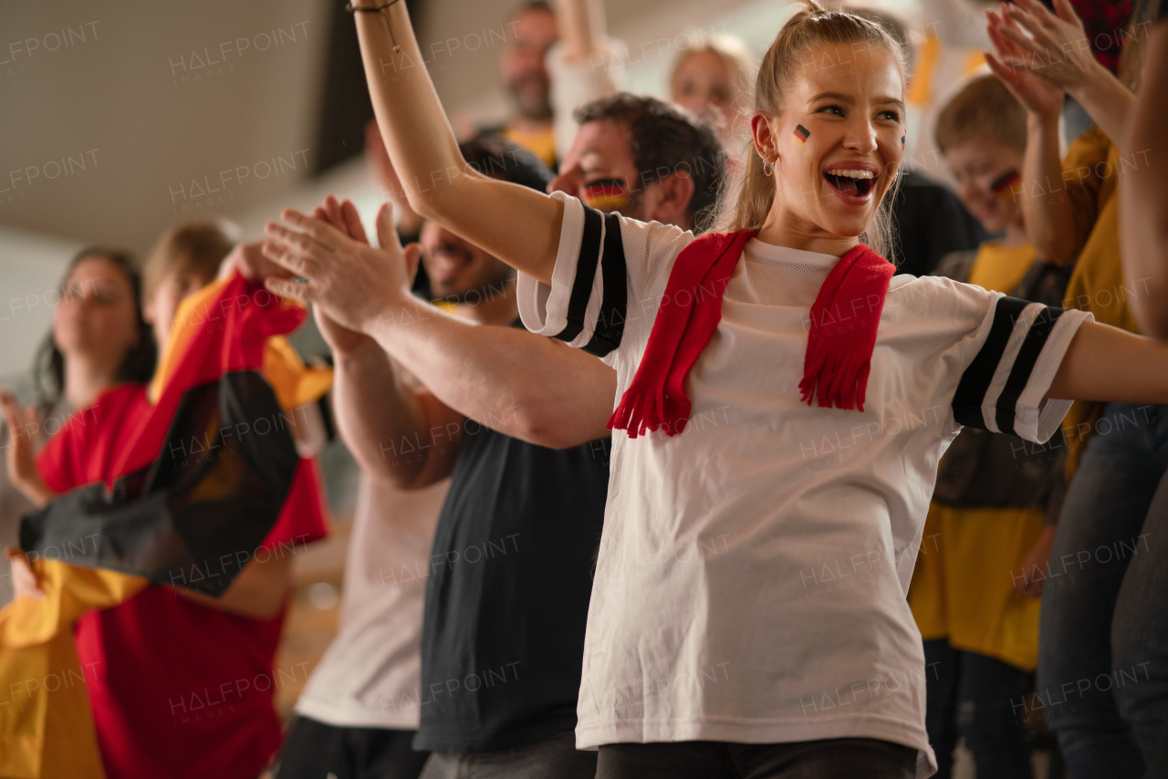 Football fans supproting a German national team in live soccer match at stadium.