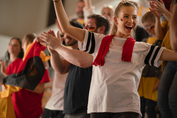 Football fans supproting a German national team in live soccer match at stadium.