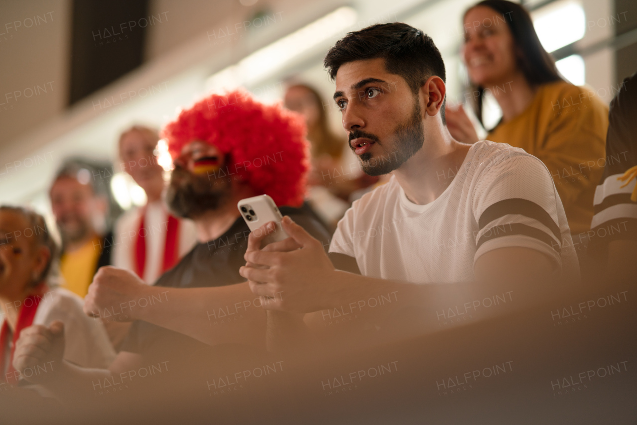 Worried football fans supproting a German national team in live soccer match at stadium.