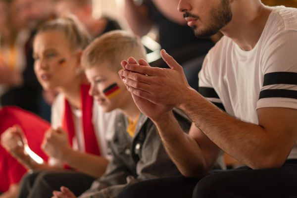 Football fans supproting a German national team in live soccer match at stadium.