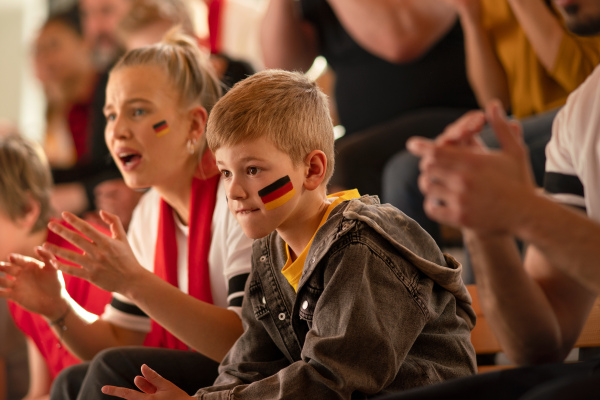 Worried football fans supproting a German national team in live soccer match at stadium.