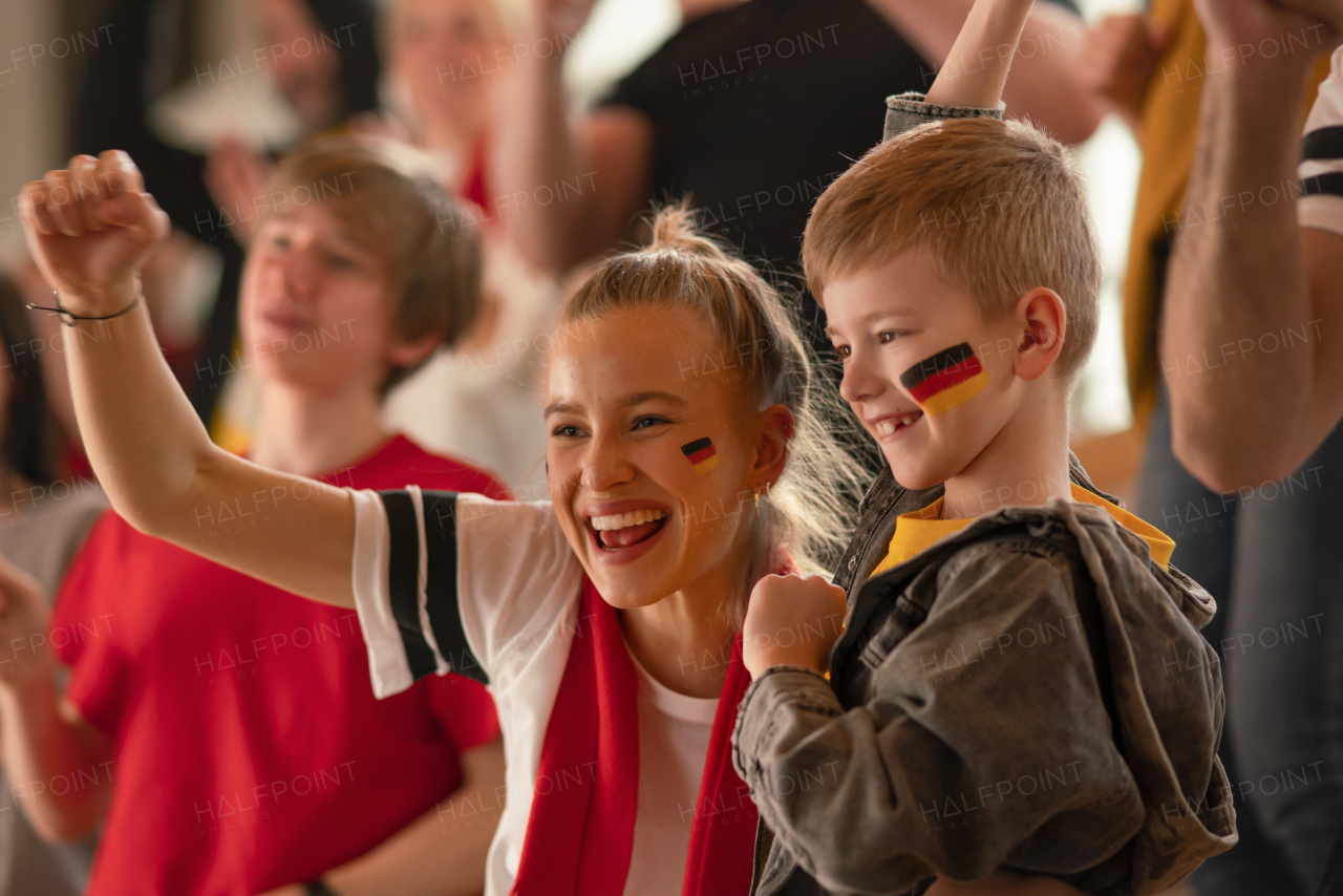 Football fans supproting a German national team in live soccer match at stadium.