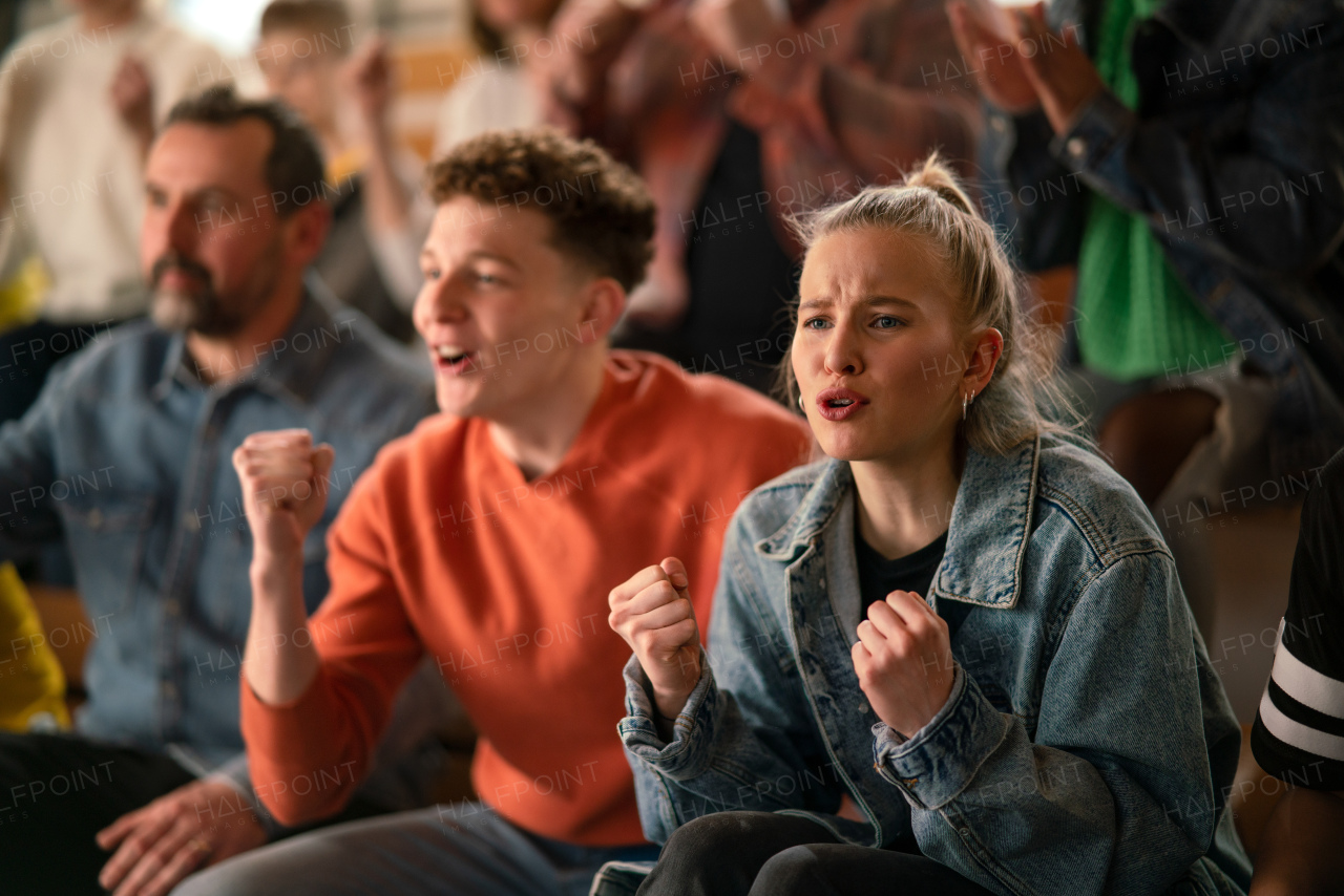 Worried fans supproting team in live match at a stadium.