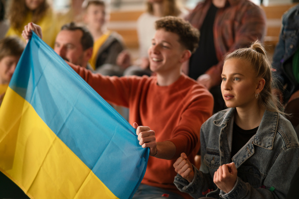 Ukrainian fans supproting national team in live match at a stadium.