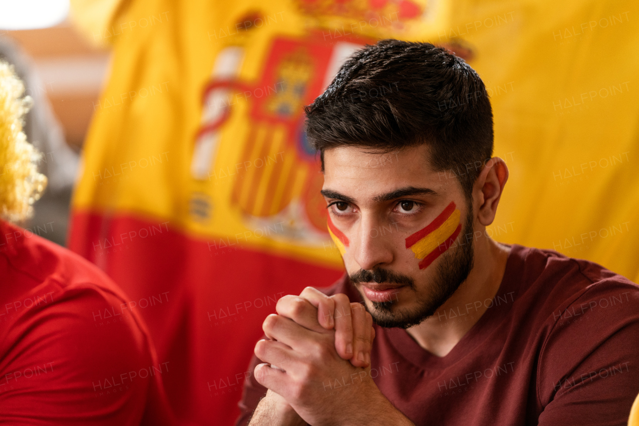 Excited football fans supproting a spanish national team in live soccer match at stadium.