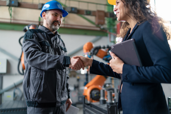 A female engineering manager and mechanic worker fist bumping in industrial factory