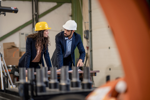 A man engineer showing machines to his collegue in industrial robotic factory.