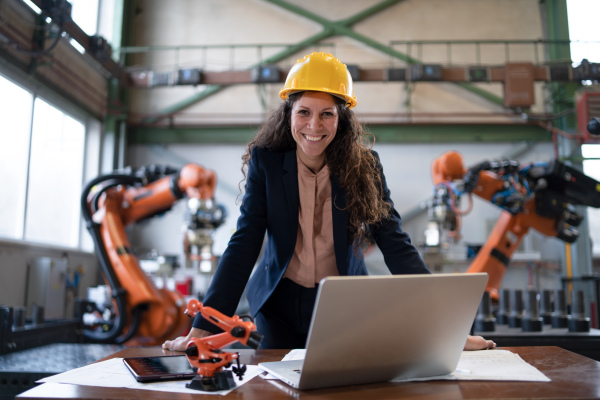 A portrait of female chief engineer in modern industrial factory using computer.