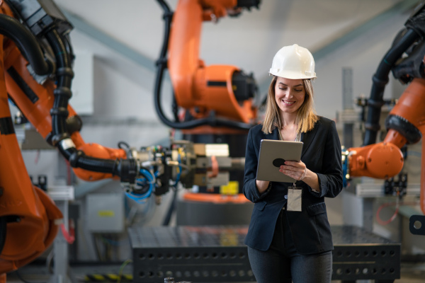 A portrait of female chief engineer in modern industrial factory using tablet.