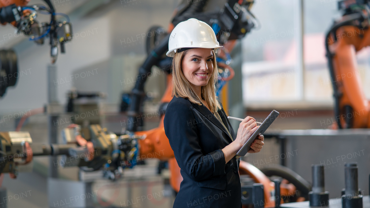 A portrait of female chief engineer in modern industrial factory using tablet.