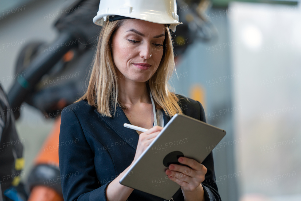 A portrait of female chief engineer in modern industrial factory using tablet.