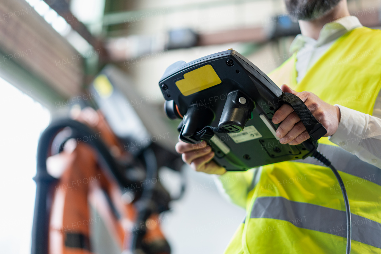 A close-up of automation engineer holding scanner in industrial in factory.