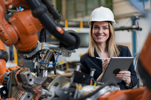 A portrait of female chief engineer in modern industrial factory using tablet.