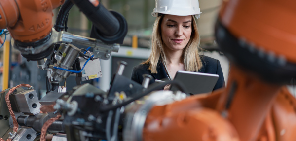 A portrait of female chief engineer in modern industrial factory using tablet.