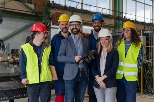 A young man worker with Down syndrome with manager and other collegues working in industrial factory, social integration concept.