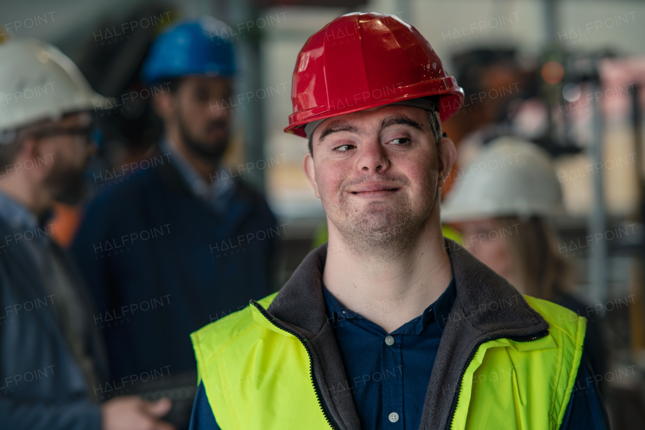 A young man with Down syndrome working in industrial factory, social integration concept.