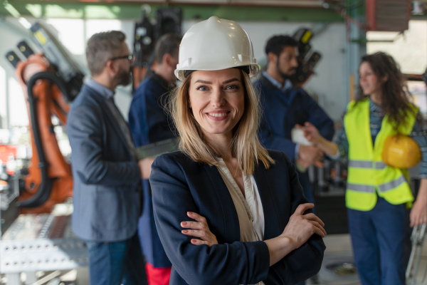 A portrait of female chief engineer in modern industrial factory looking at camera.