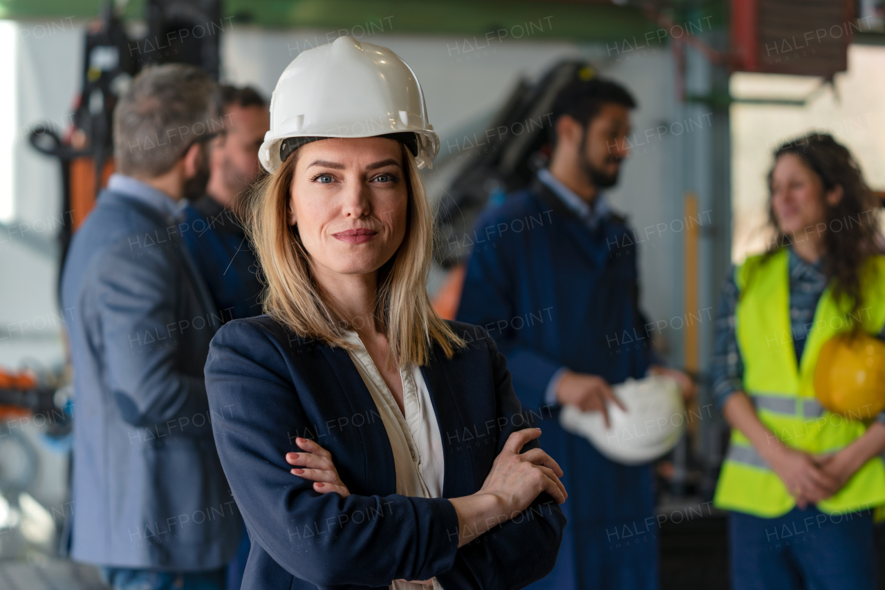 A portrait of female chief engineer in modern industrial factory looking at camera.