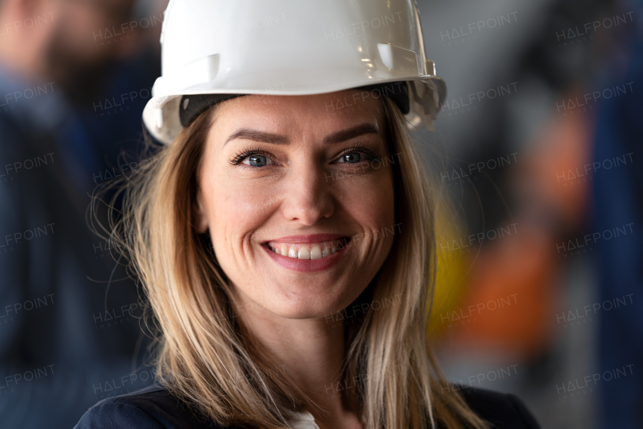 A portrait of female chief engineer in modern industrial factory looking at camera.