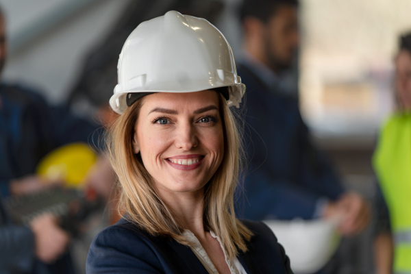 A portrait of female chief engineer in modern industrial factory looking at camera.