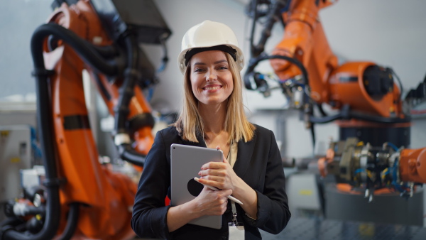 A portrait of female chief engineer in modern industrial factory using tablet.