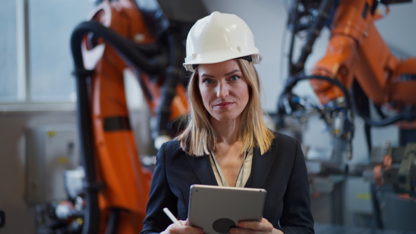 A portrait of female chief engineer in modern industrial factory using tablet.