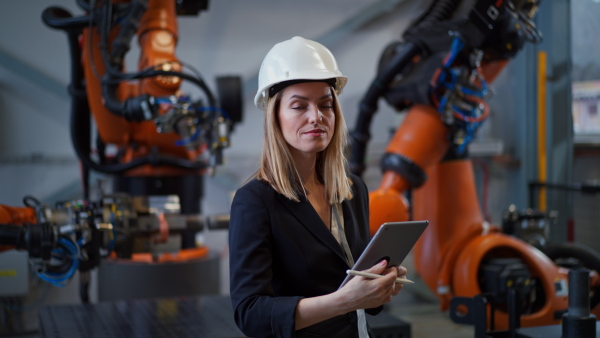 A portrait of female chief engineer in modern industrial factory using tablet.