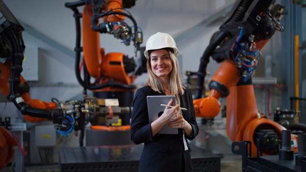 A portrait of female chief engineer in modern industrial factory using tablet.